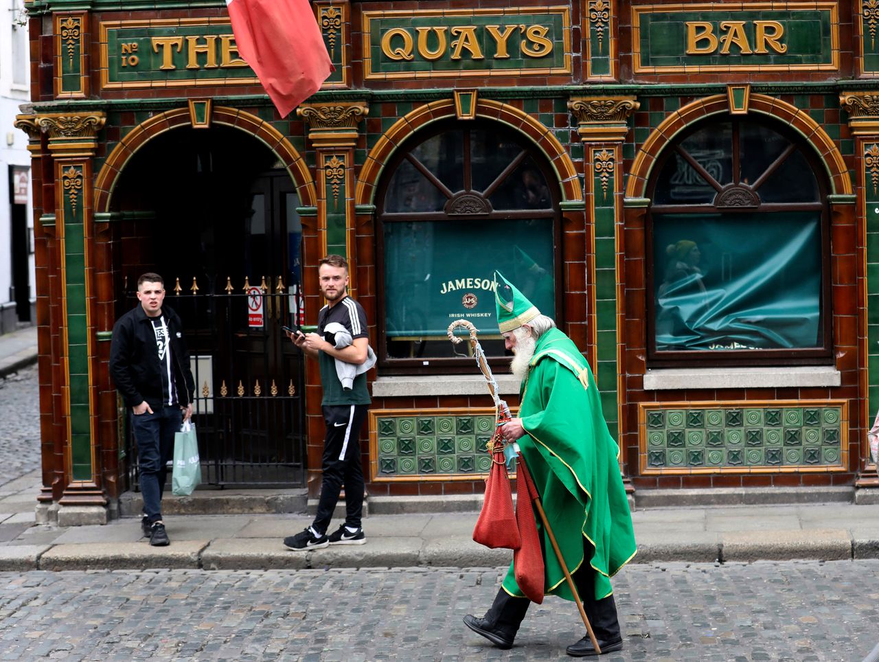 Ένας άνδρας ντυμένος σαν τον άγιο Πατρίκιο περνά μπροστά από μια Pub στο Δουβλίνο 16 Μαρτίου 2020.(AP Photo/Peter Morrison)