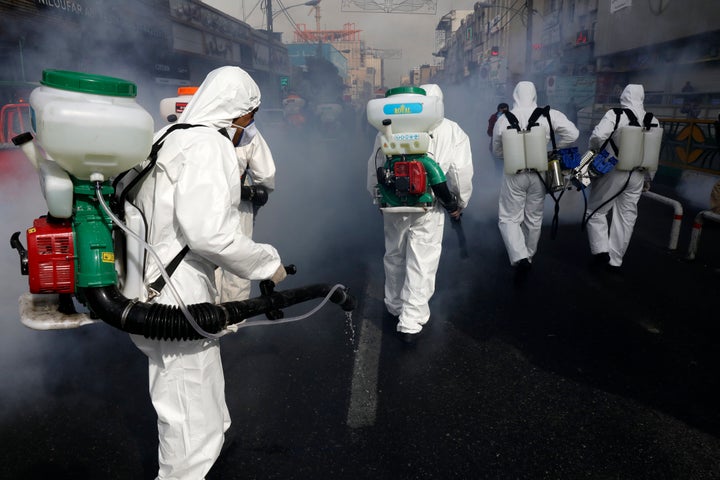 Firefighters disinfect a street against the new coronavirus, in western Tehran, Iran, Friday, March 13, 2020. (AP Photo/Vahid