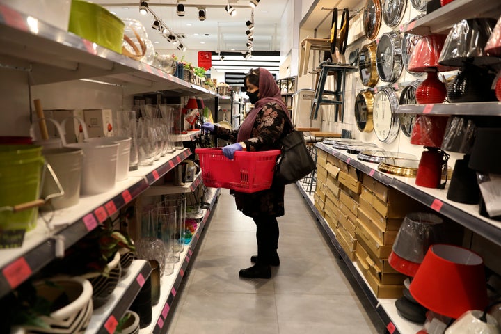 A woman wearing a face mask shops at a store in Bamland shopping mall, in Western Tehran, Iran, Sunday, March 15, 2020. (AP P