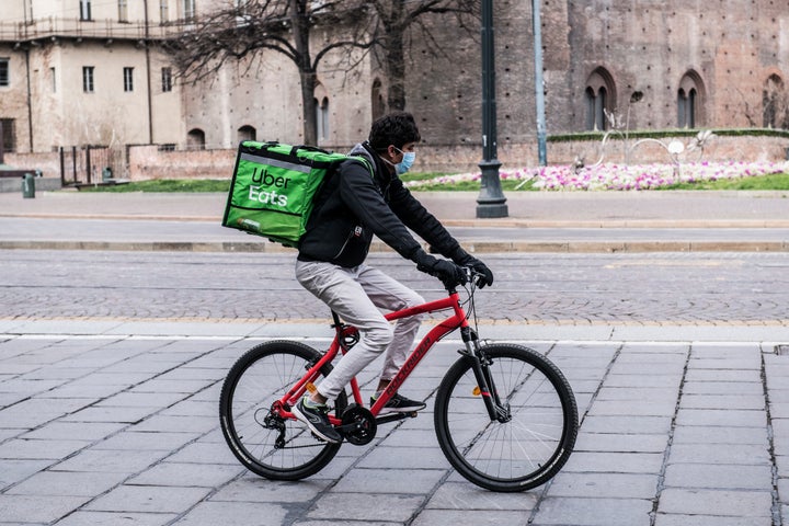 Na Itália, epicentro do contágio fora da Ásia, entregadores utilizam máscaras enquanto trabalham. 