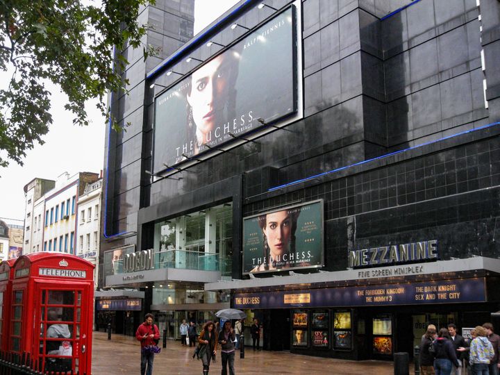 The facade of the modern Odeon Cinema and the typical red telephone booths in Leicester Square, London, England.