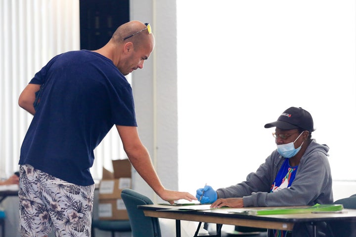 A poll worker provides a voter with a ballot during the Florida presidential primary on March 17, 2020, in Miami.