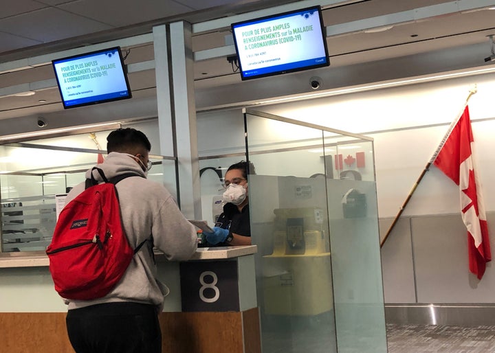 A Canada Border Services Agency officer wears a protective face mask amid coronavirus fears as she checks passports for those arriving at Toronto Pearson International Airport in Toronto on March 15, 2020.