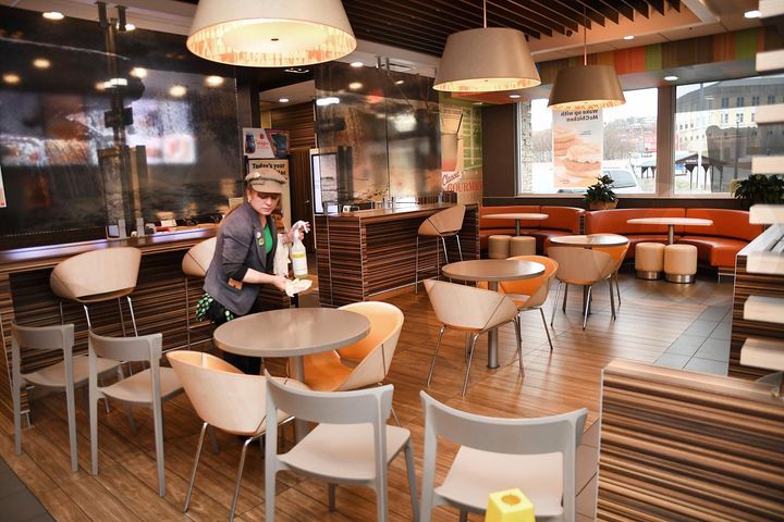 Lori Harper, manager, wipes down tables in the dining room area of the McDonald's on Prince Street in Beckley Tuesday morning, March 17, 2020. McDonald's closed off the dining section and will provide drive-through service along with walk-in orders placed at the front counter. Customers are not allowed to eat their meals in the restaurant because of the coronavirus. (Rick Barbero/The Register-Herald via AP)