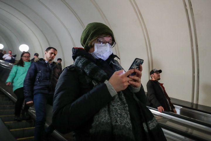 A woman wears a face mask while using her cellphone as she enters a Moscow Underground station during the coronavirus pandemic.