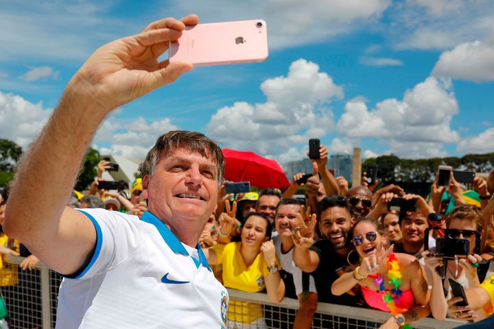 Brazilian President Jair Bolsonaro takes a selfie with supporters in front of the Planalto Palace on March 15, 2020. 
