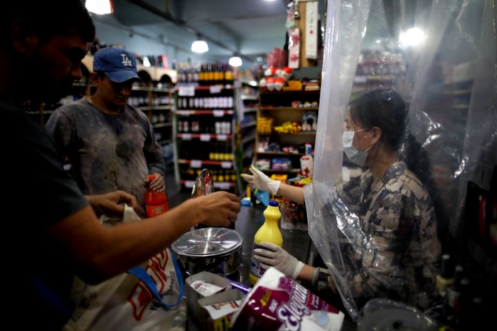 Μπουένος Άιρες, Αργεντινή: Ταμίας σε σούπερ μάρκετ στέκεται πίσω από μια αυτοσχέδια πλαστική κουρτίνα και προσπαθεί να εξυπηρετήσει τους πελάτες.