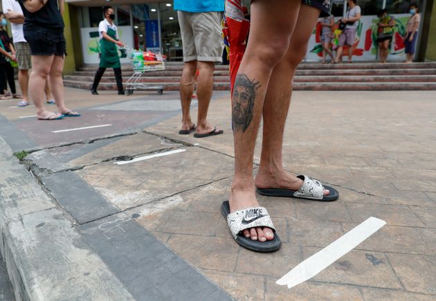 Μανίλα, Φιλιππίνες: Ενας νεαρός περιμένει στην ουρά για το σούπερ μάρκετ. Εκτός από τον Ιησού, που έχει τατουάζ στο πόδι του, ευελπιστεί ότι και η απόσταση από τους γύρω του να τον σώσει.