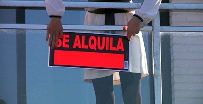 Imagen de archivo de una propietaria colgando un cartel de alquiler