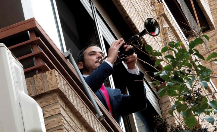 Un hombre toca la trompeta desde una ventana.