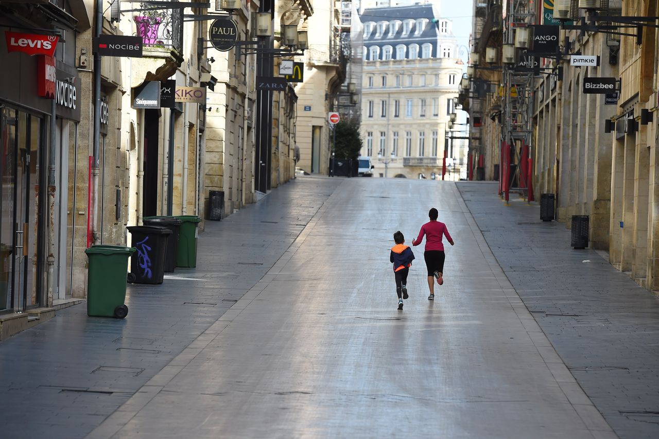 A woman and her son run in the deserted Sainte-Catherine street in Bordeaux, southwestern France