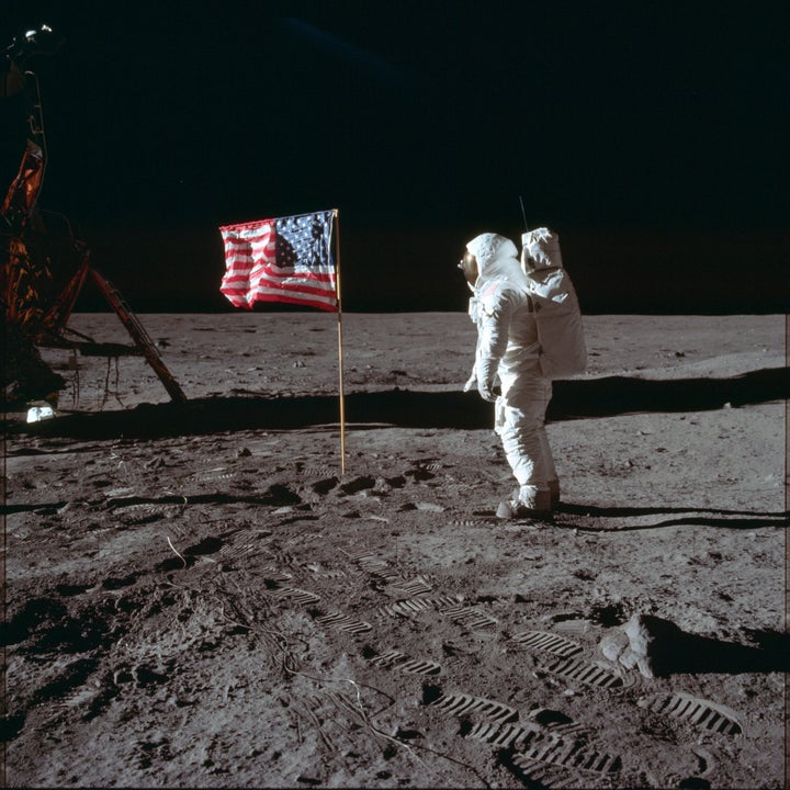 Buzz Aldrin faces the flag on the moon.