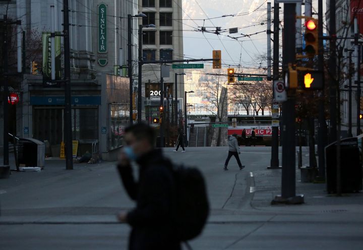 People wearing face masks walk around Vancouver. The British Columbia government has declared a provincial state of emergency.