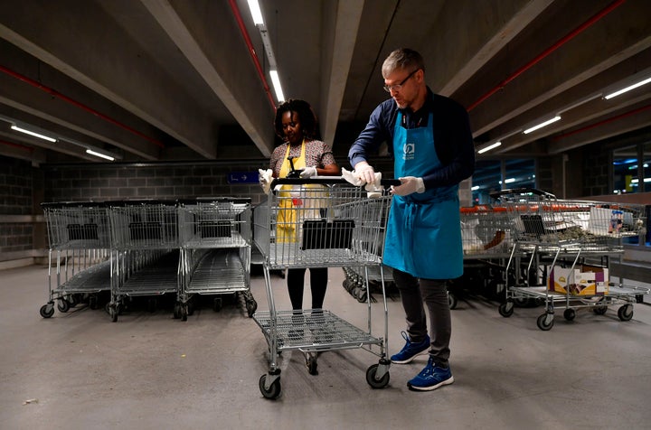 Members of a supermarket in Belgium disinfect a trolley to help stop the spread of the coronavirus.