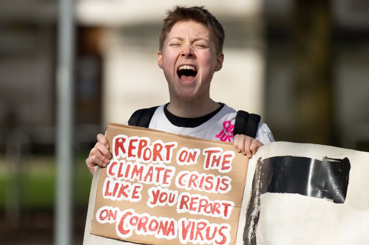 A Youth Climate Strike protestor holds a sign referencing coronavirus on March 13, 2020 in Cardiff, Wales. 