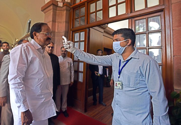 NEW DELHI, INDIA- MARCH 18: A security official checks the temperature of Vice president M. Venkaiah Naidu with an infrared thermometer as a precaution against the new coronavirus during the ongoing Budget Session, at the Parliament House, on March 18, 2020 in New Delhi, India. Prime Minister Narendra Modi on Tuesday told parliamentarians of the ruling Bharatiya Janata Party (BJP) that the ongoing budget session would continue till 3 April and the session would not be curtailed because of the threat posed by the coronavirus outbreak. (Photo by Sonu Mehta/Hindustan Times via Getty Images)