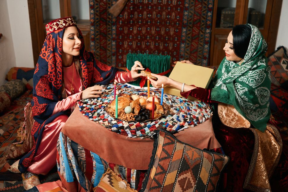 Novruz holiday celebration with azeri women and novruz tray with traditional pastry shekerbura and pakhlava food.