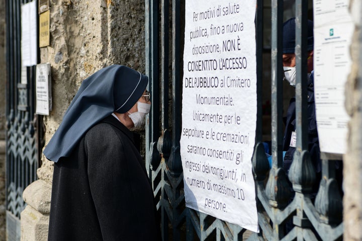 A nun wearing a face mask looks inside the closed Monumental Cemetery of Bergamo, Lombardy, on March 20, 2020 during the country's lockdown aimed at stopping the spread of the COVID-19 (new coronavirus) pandemic. (Photo by Piero Cruciatti / AFP) (Photo by PIERO CRUCIATTI/AFP via Getty Images)