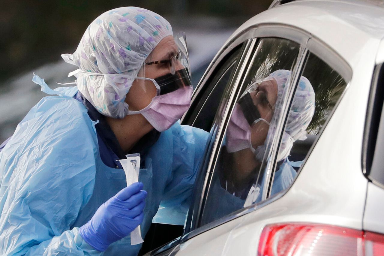 Laurie Kuypers, a registered nurse, reaches into a car to take a nasopharyngeal swab from a patient at a drive-through COVID-19 coronavirus testing station for University of Washington Medicine patients Tuesday, March 17, 2020, in Seattle. The appointment-only drive-through clinic began a day earlier. Health authorities in Washington reported more COVID19 deaths in the state that has been hardest hit by the outbreak. (AP Photo/Elaine Thompson)
