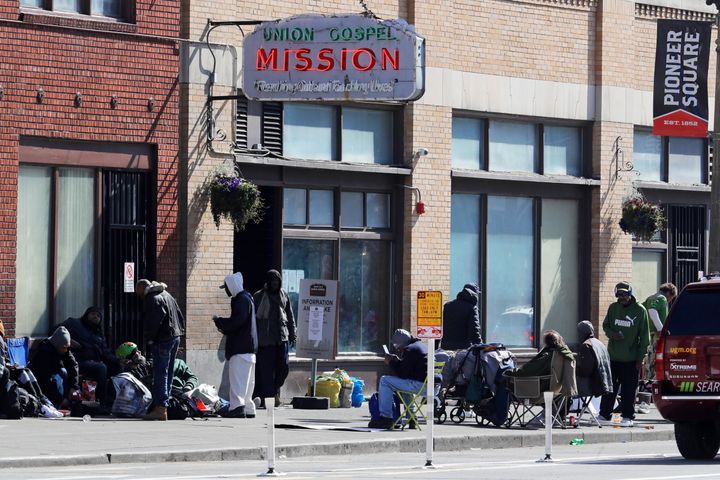 People gather on the sidewalk in front of the Union Gospel Mission in downtown Seattle on Friday. The mission serves a large portion of Seattle's homeless population, and officials fear that controlling the spread of the new coronavirus in groups that lack access to basic hygiene and other supplies will be difficult. 