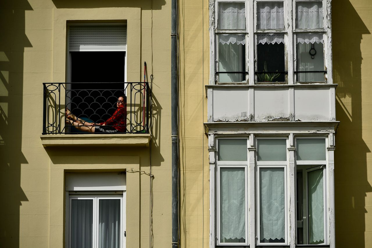 Μια γυναίκα σε καραντίνα κάθεται στο μικρό μπαλκόνι της στη Vitoria στη Βόρεια Ισπανία. 19 Μαρτίου 2020.(AP Photo/Alvaro Barrientos)
