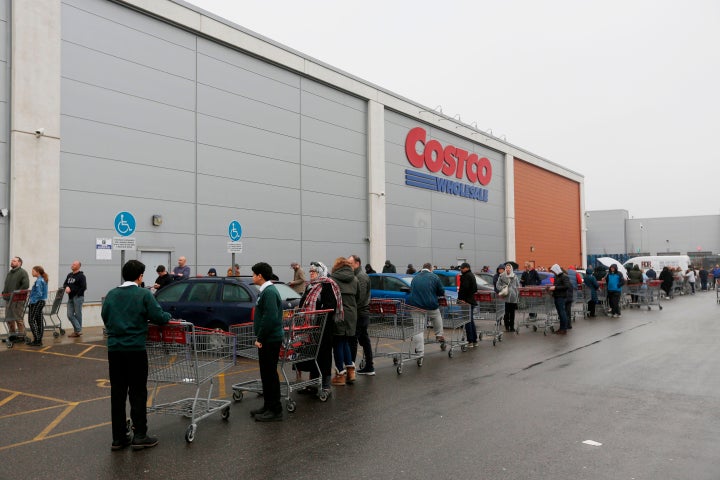 Customers wait in a long queue to enter a Costco outlet in Farnborough, west of London, England. March 19, 2020.