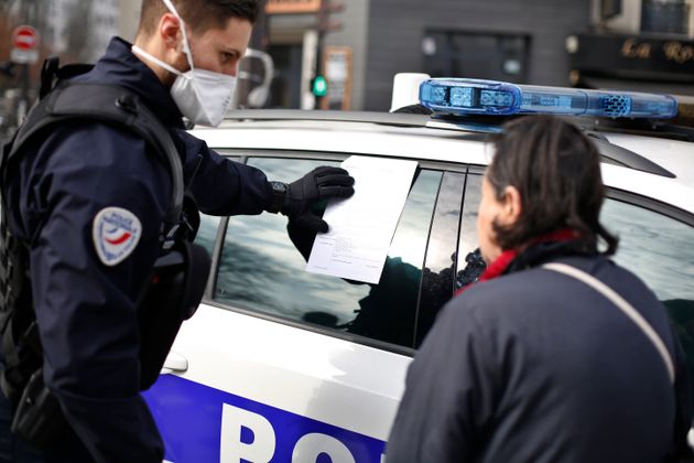 À Paris le 20 mars 2020, un policier verbalise une passante pour non respect des règles...