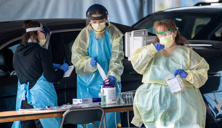 Medical personnel wearing protective equipment screen people referred by doctors for COVID-19 testing, Friday, March 20, 2020