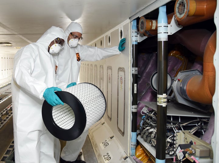 Members of cleaning staff in protective suits change air filters on an Emirates aircraft as part of disinfectant measures against the coronavirus.