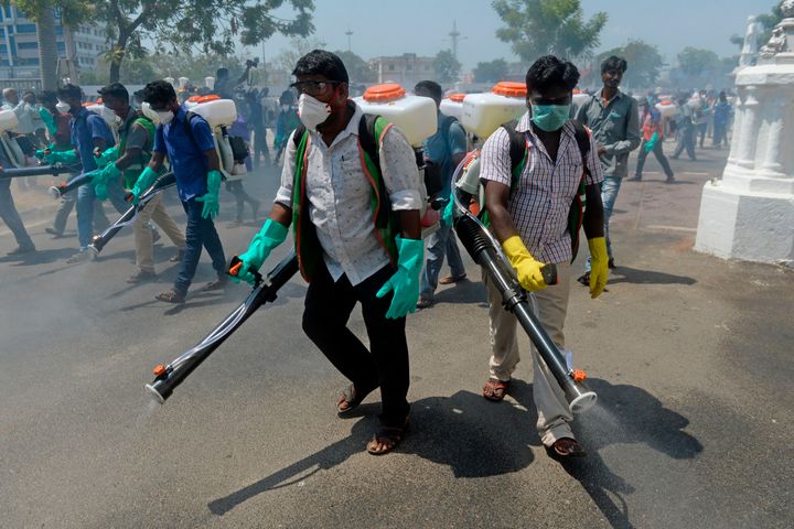 Health workers wearing facemasks amid concerns over the spread of the COVID-19 novel coronavirus, spray disinfectant at the corporation office in Chennai on March 20, 2020. 