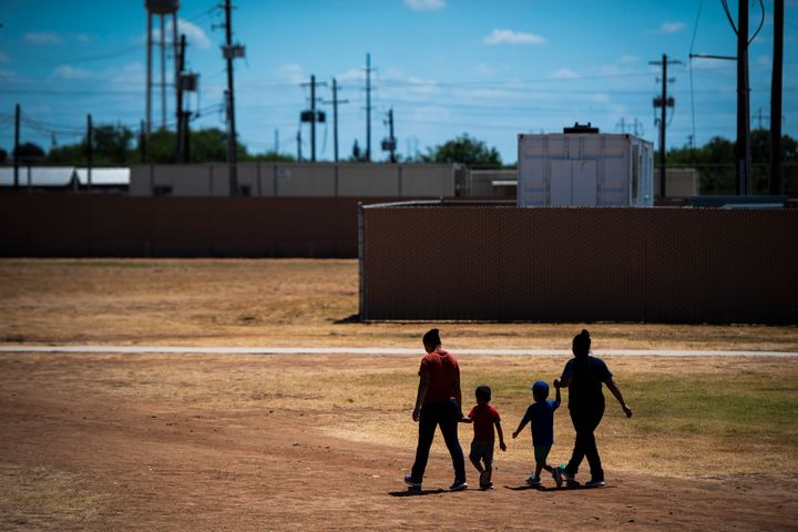 Immigrant women and children walk across a field as Immigration and Customs Enforcement and Enforcement and Removal Operations host a media tour at the South Texas Family Residential Center last summer in Dilley, Texas.