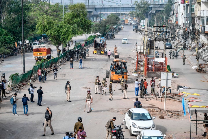 Security personnel patrol as a crane is used to clean the streets in Shaheen Bagh area after removing demonstrators on March 24, 2020.