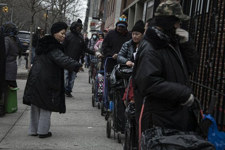 Sheila Williams, left, who manages the soup kitchen and food pantry at St. Stephen Outreach, tells people waiting in line for their food donations to keep bigger distances between one another, in the Brooklyn borough of New York, on Friday, March 20, 2020. 