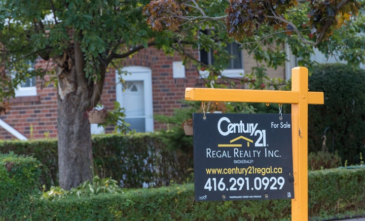 In this file photo, a Century 21 for-sale sign is seen on a lawn in Toronto, Oct. 12. 2016. The Ontario Real Estate Association is calling for an end to person-to-person contact in home sales.