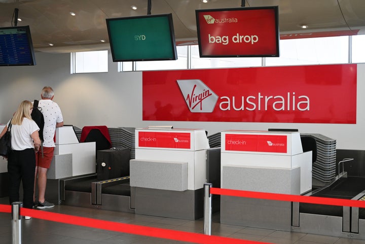 Travelers stand at a Virgin Australia Airlines counter at Kingsford Smith International Airport, following the coronavirus outbreak, in Sydney, Australia, March 18, 2020. REUTERS/Loren Elliott