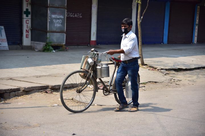 A milkman pushes a bicycle during a nationwide lockdown in the wake of coronavirus pandemic, in Nagaon District of Assam.
