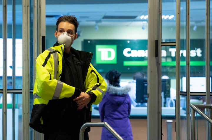 A security guard at a TD Bank wears a mask as he limits the number of clients in the bank to help prevent the spread of COVID-19 in Ottawa on March 24, 2020. 