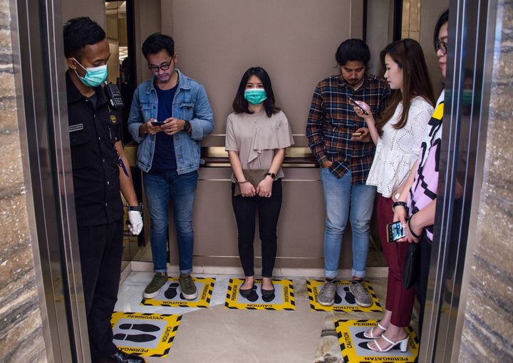 People stand on designated areas to ensure social distancing inside an elevator at a shopping mall in Surabaya, Indonesia. This is actually closer contact than the Centers for Disease Control and Prevention recommends.
