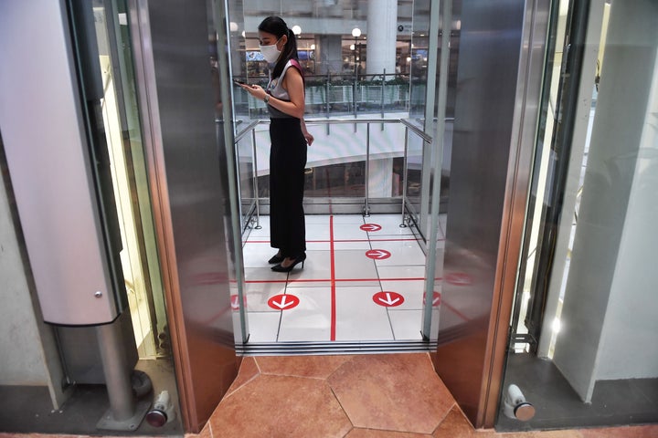 A woman stands in an elevator with markers on the floor for social distancing measures in a shopping mall in Bangkok on March 20. 