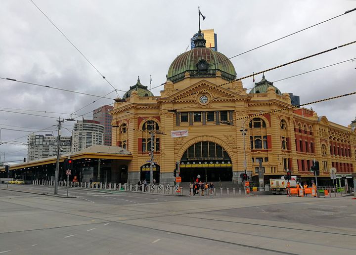 Mobile photo shows few people standing in front of the Flinders Street Station in Melbourne, Australia, March 25, 2020. 