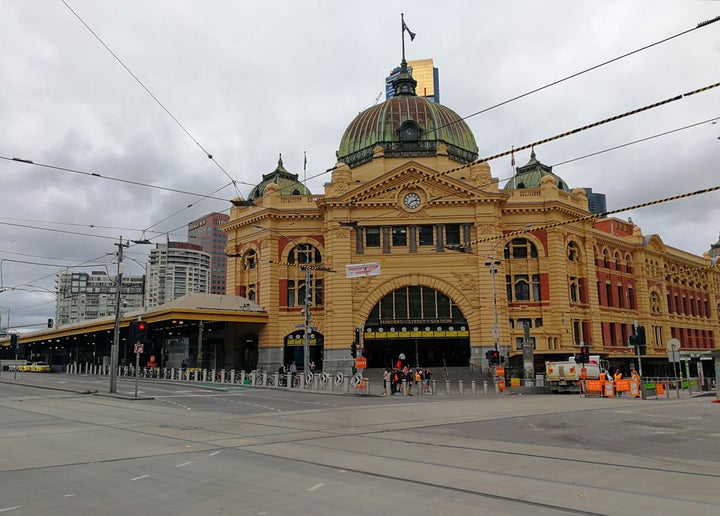 Mobile photo shows few people standing in front of the Flinders Street Station in Melbourne, Australia, March 25, 2020.