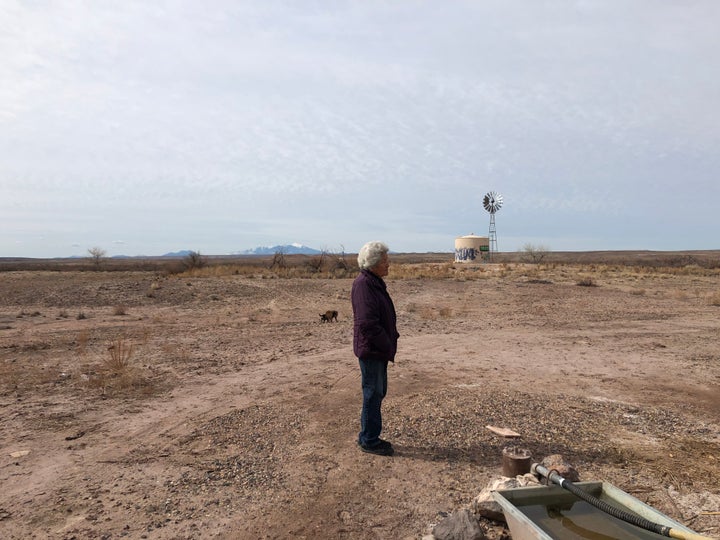 Shanna Yazzie's 79-year-old mother stands by the nearby windmill pump the family relies on for bathing water. 