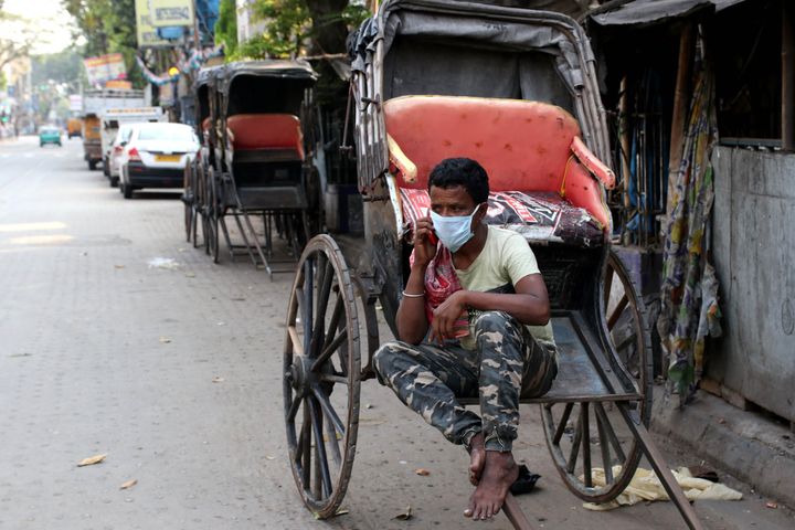 A Hand rickshaw pullers wearing a protective mask taking towards his Mobile phone on a deserted road during the first day of a 21-day government-imposed nationwide lockdown as a preventive measure against the COVID-19 coronavirus in Kolkata on March 25, 2020. More than one billion Indians went into lockdown on March 25, leaving a third of the planet now under orders to stay at home, as the United States vowed to spend $2 trillion to counter the economic harm of the coronavirus. (Photo by Debajyoti Chakraborty/NurPhoto via Getty Images)