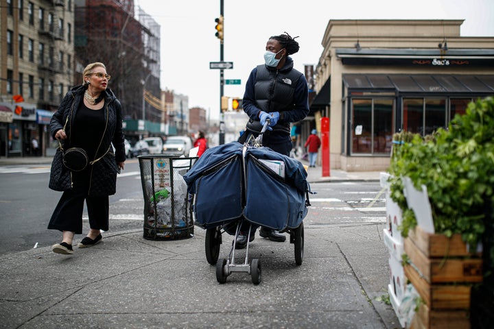 A postal worker wears a mask and gloves while operating a route in the Queens borough of New York City.