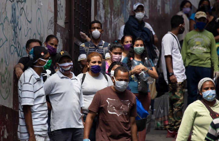 People line up to buy food and disinfectant, some wearing face masks as a preventive measure against the spread of the new coronavirus in Caracas, Venezuela, on March 26, 2020.