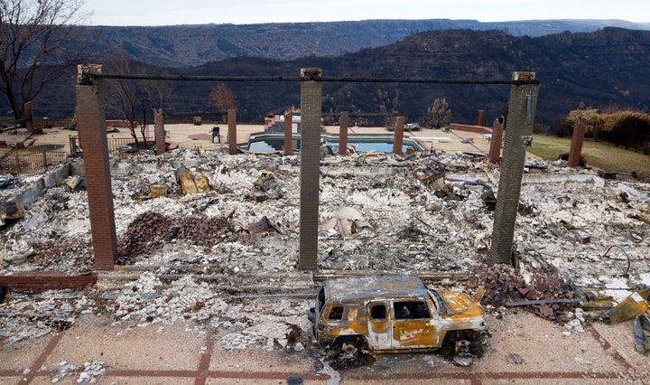 A burned-out vehicle rests in front of a home leveled by the Camp Fire in Paradise, California, in 2018.