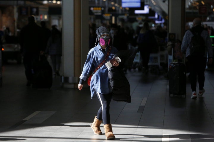 A woman wearing a protective face mask and goggles walks through Vancouver International Airport in Richmond, B.C. on March 16, 2020.