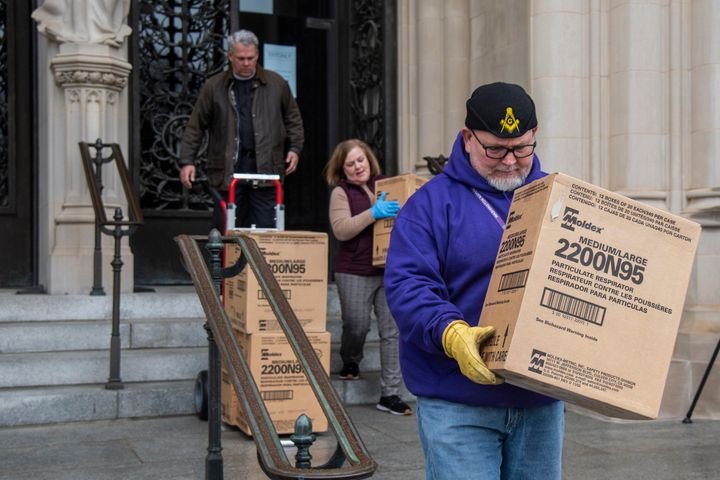 People transport boxes of N95 respirator masks out of the Washington National Cathedral on March 25, 2020.