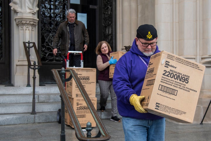 People transport boxes of N95 respirator masks out of the Washington National Cathedral on March 25, 2020.