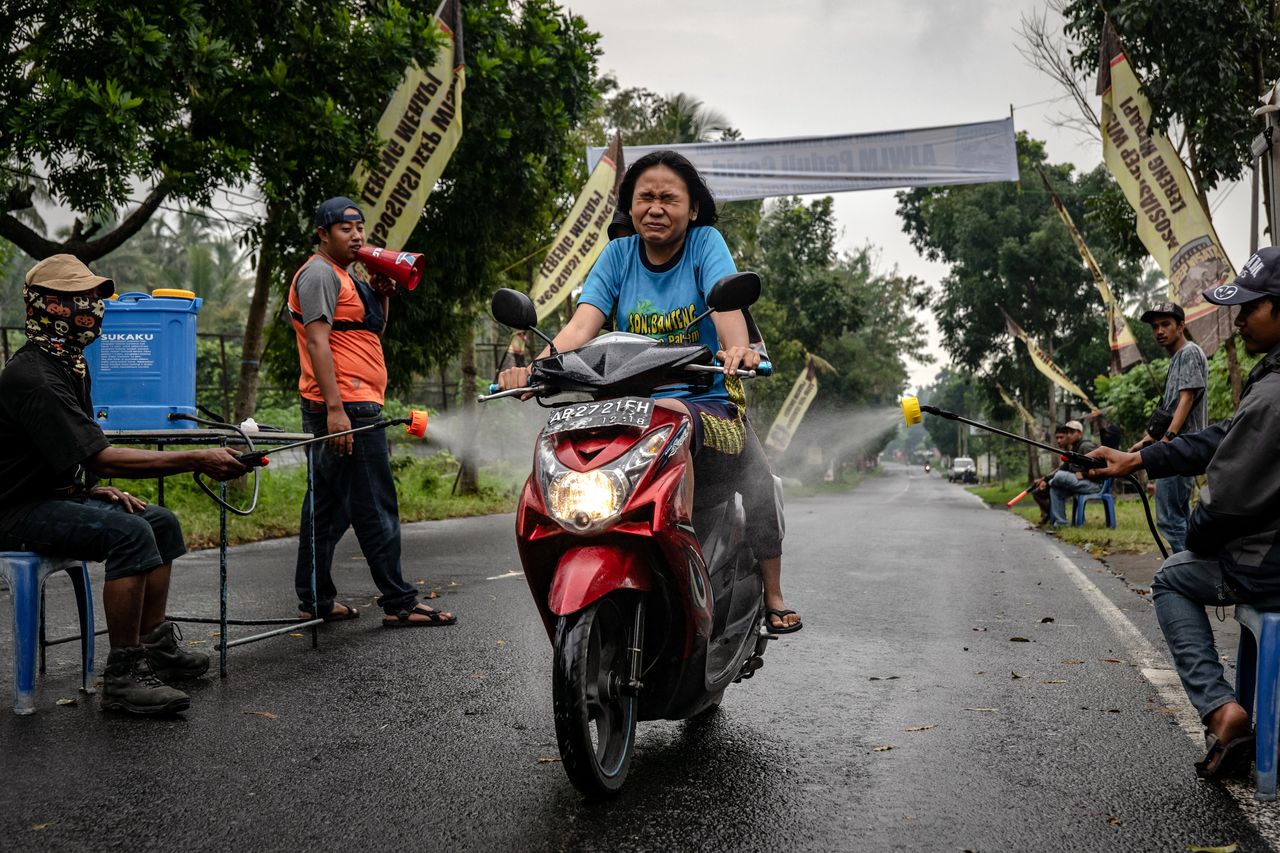 Κάτοικοι στην πόλη Γιογκιακάρτα, της Ινδονησίας, ψεκάζουν με απολυμαντικό σπρέι, διερχόμενο μοτοσυκλετιστή, προκειμένου να αποτρέψουν την εξάπλωση του κορονοϊού, με τις αρχές να έχουν επιβεβαιώσει περισσότερους από 1.000 νεκρούς. Παρασκευή, 27 Μαρτίου, 2020.